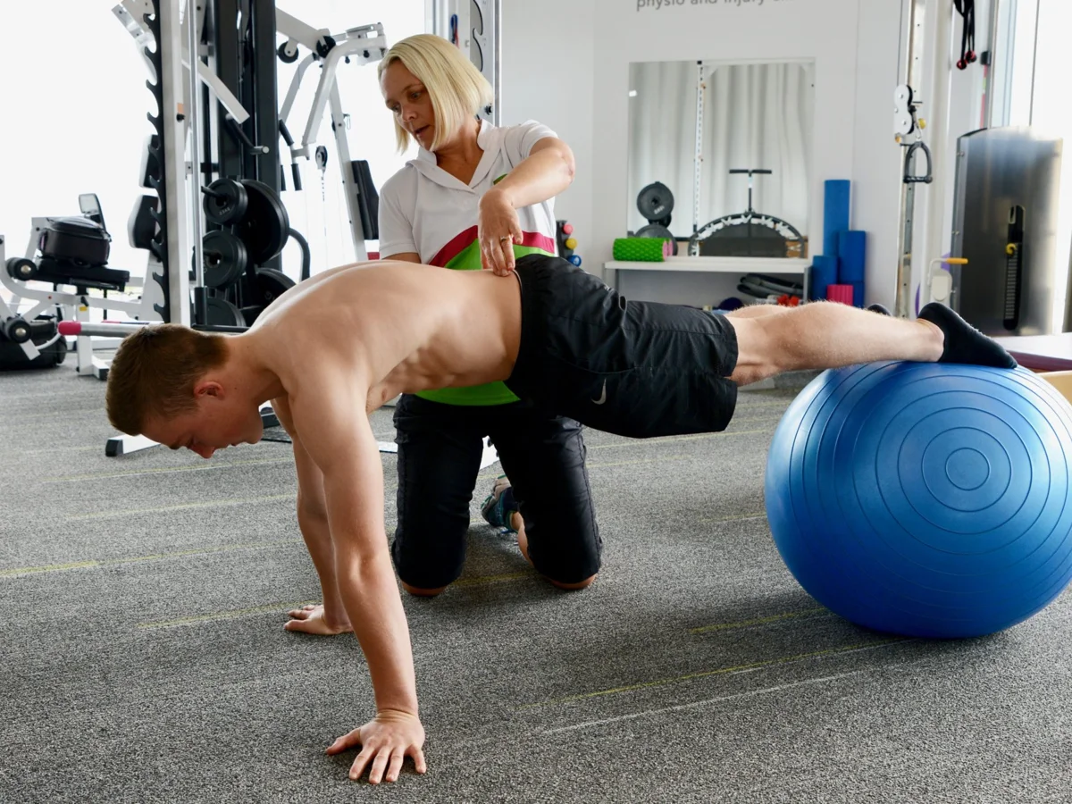 Cat Croghan guiding a patient through a fitball exercise in the Phyxit gym